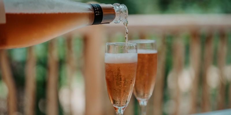 Two glasses being filled on the terrace of a lodge in Calviac