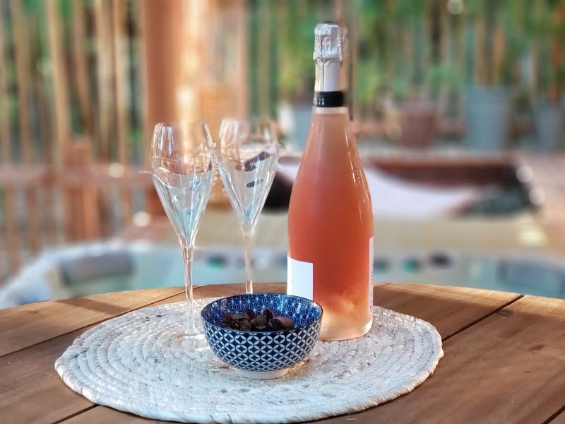 Deux verres et une bouteille avec un petit bol d'apéritif sur une table d'une terrasse d'un lodge