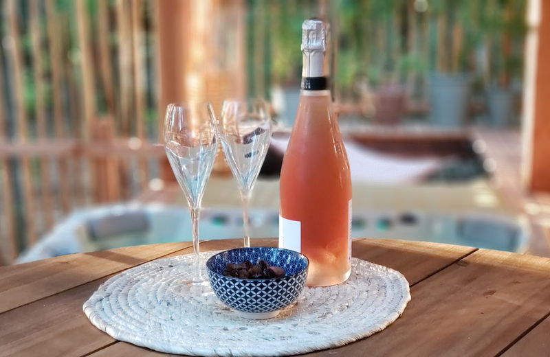 Deux verres et une bouteille avec un petit bol d'apéritif sur une table d'une terrasse d'un lodge