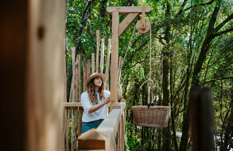 Une femme avec un chapeau récupère le panier du petit déjeuner dans son lodge