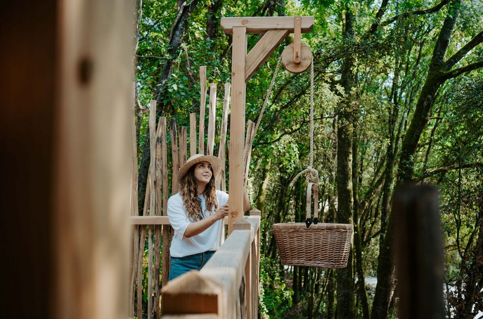 Une femme avec un chapeau récupère le panier du petit déjeuner dans son lodge