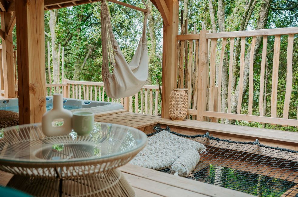 Vu sur l'extérieur depuis la terrasse du lodge avec la petite table, le filet et le spa