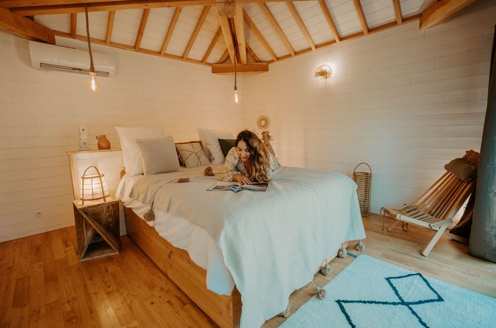 A woman reading a book on the double bed at the Kali lodge in Calviac