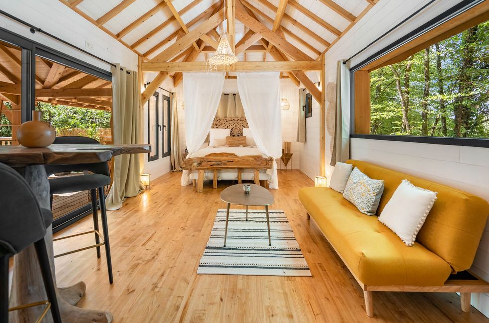 Interior of the Shiva lodge with the bed, the sofa, its small table and the high table with its two high chairs in Calviac